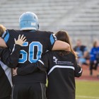 A football player gets escorted off the field by two athletic trainers.