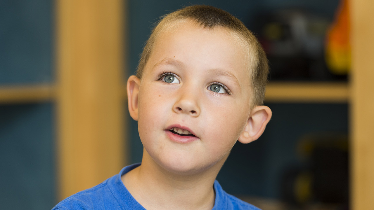 Headache Program Young boy in blue shirt looks up.